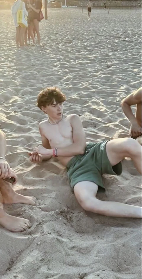 A group of young men laying on top of a sandy beach.