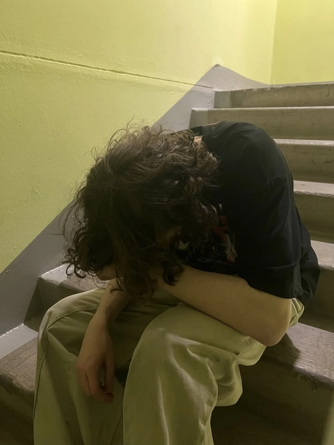 A woman sitting on the steps of a building with her head in her hands.