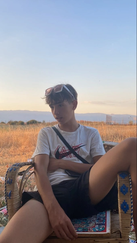 A man sitting on top of a wicker chair in a field.