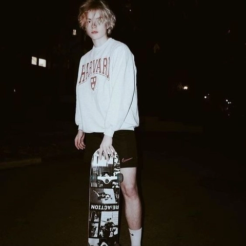 A young man holding a skateboard in his hands.
