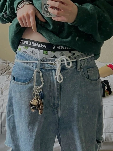 A woman wearing a pair of jeans with a chain around her waist.