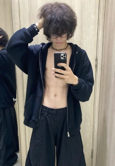 A shirtless man taking a selfie in front of a mirror.
