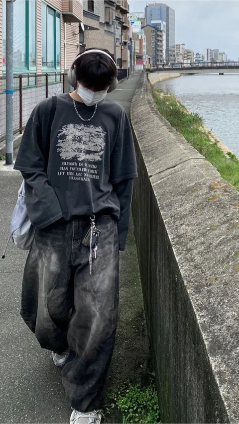 A man wearing a mask standing next to a wall.