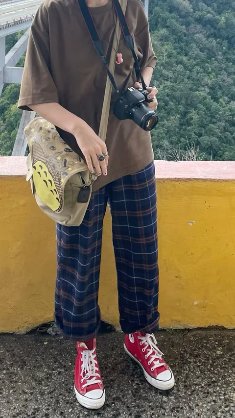 A woman standing on a bridge holding a camera.