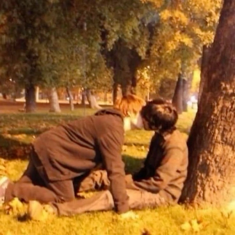 A couple of people sitting on top of a grass covered field.