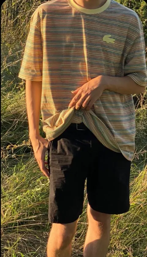 A man wearing a shirt and shorts standing in a field.