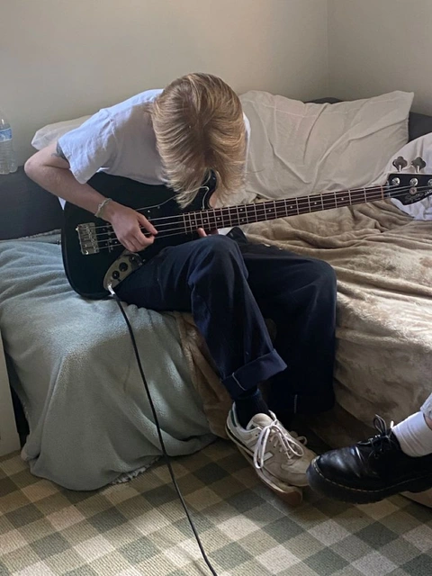 A man sitting on a bed playing a guitar.