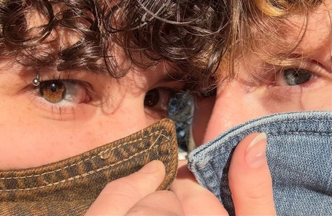 A close up of a person's face with a pair of jeans covering their eyes.