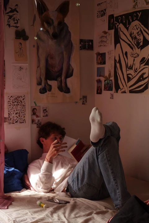 A man sitting on a bed with his feet up in the air.