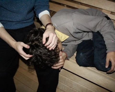 A group of people sitting on top of a wooden bench.