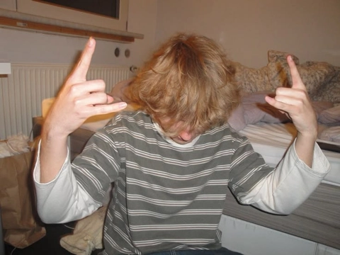 A man sitting on top of a couch with his hands up.
