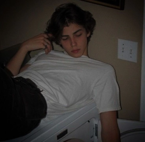 A young man laying on top of a bed.