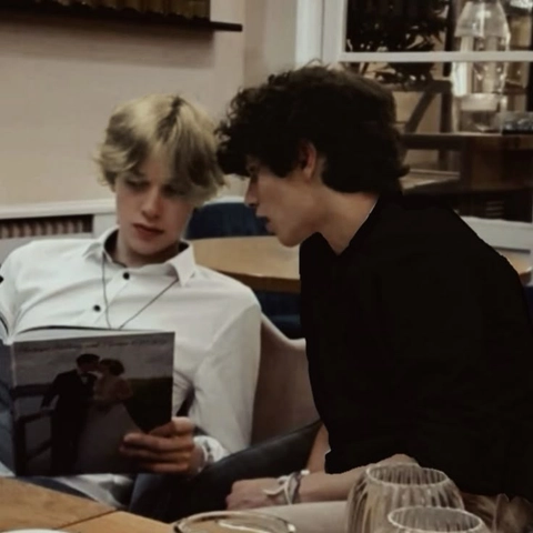 A couple of people sitting at a table with a book.