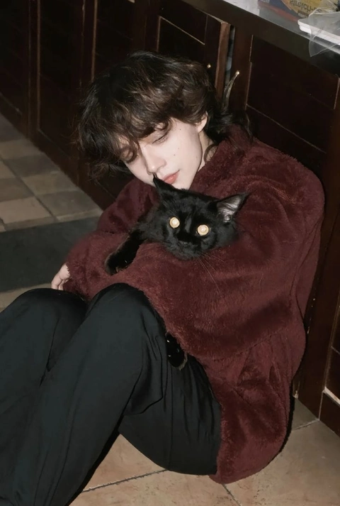 A woman in a red coat holding a black cat.