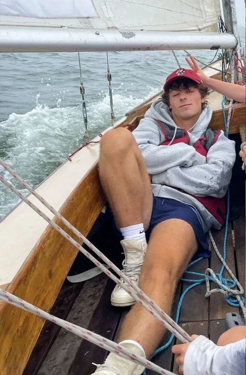 A man sitting on the deck of a boat in the ocean.