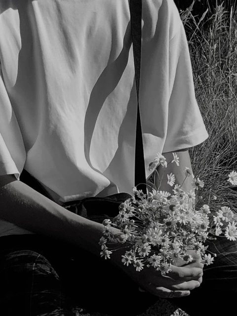 A black and white photo of a person holding a bunch of flowers.
