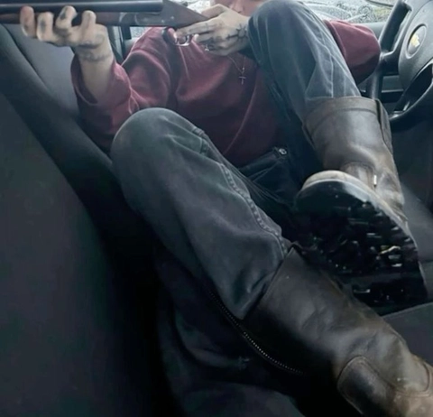 A man sitting in the back seat of a car with his feet up.