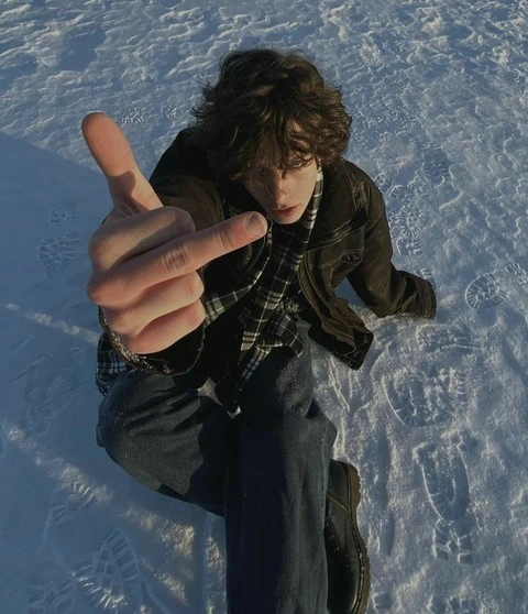 A man sitting in the snow with his hands up.
