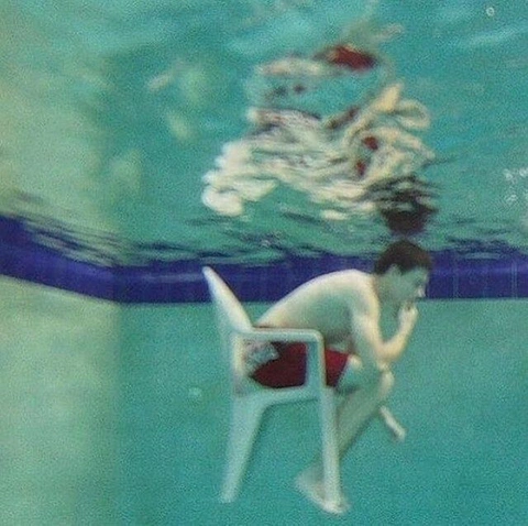 A man sitting on a chair under water.