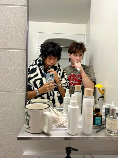 A couple of people taking a picture of themselves in a mirror.