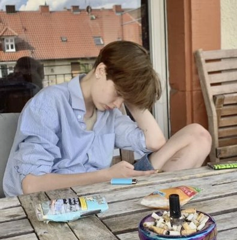 A man sitting at a table with cigarettes in front of him.