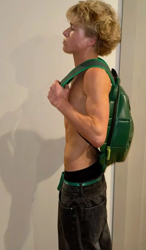 A man with a backpack standing in front of a mirror.
